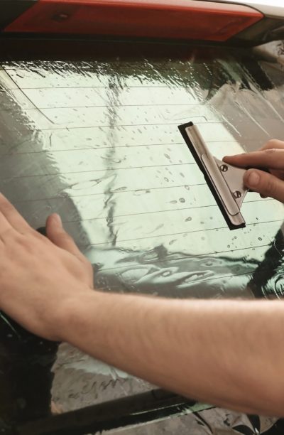 Worker applying tinting foil onto car window